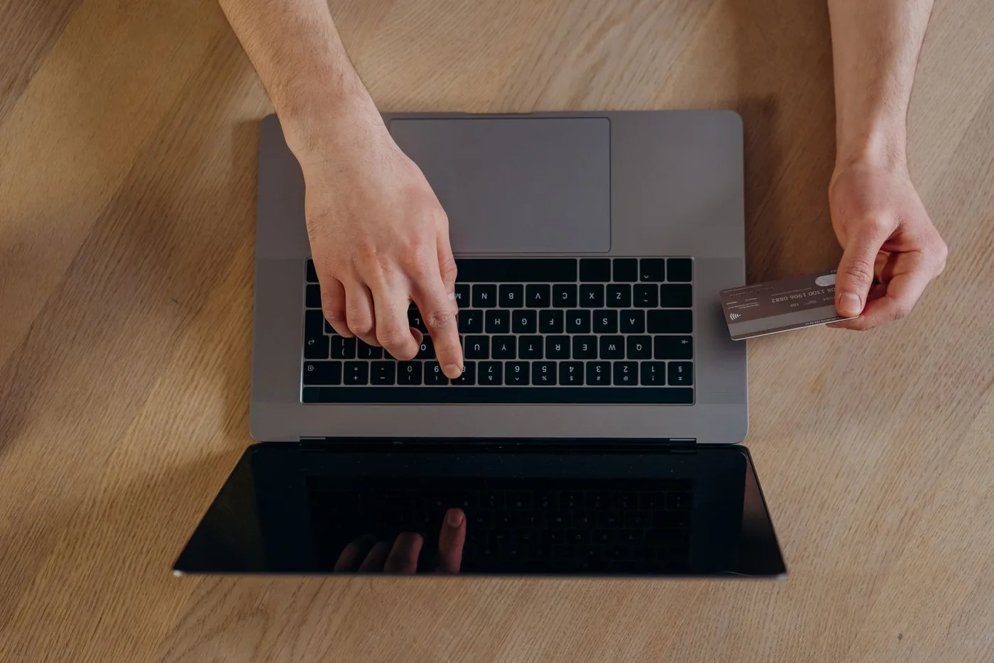 Hands paying by card at a laptop