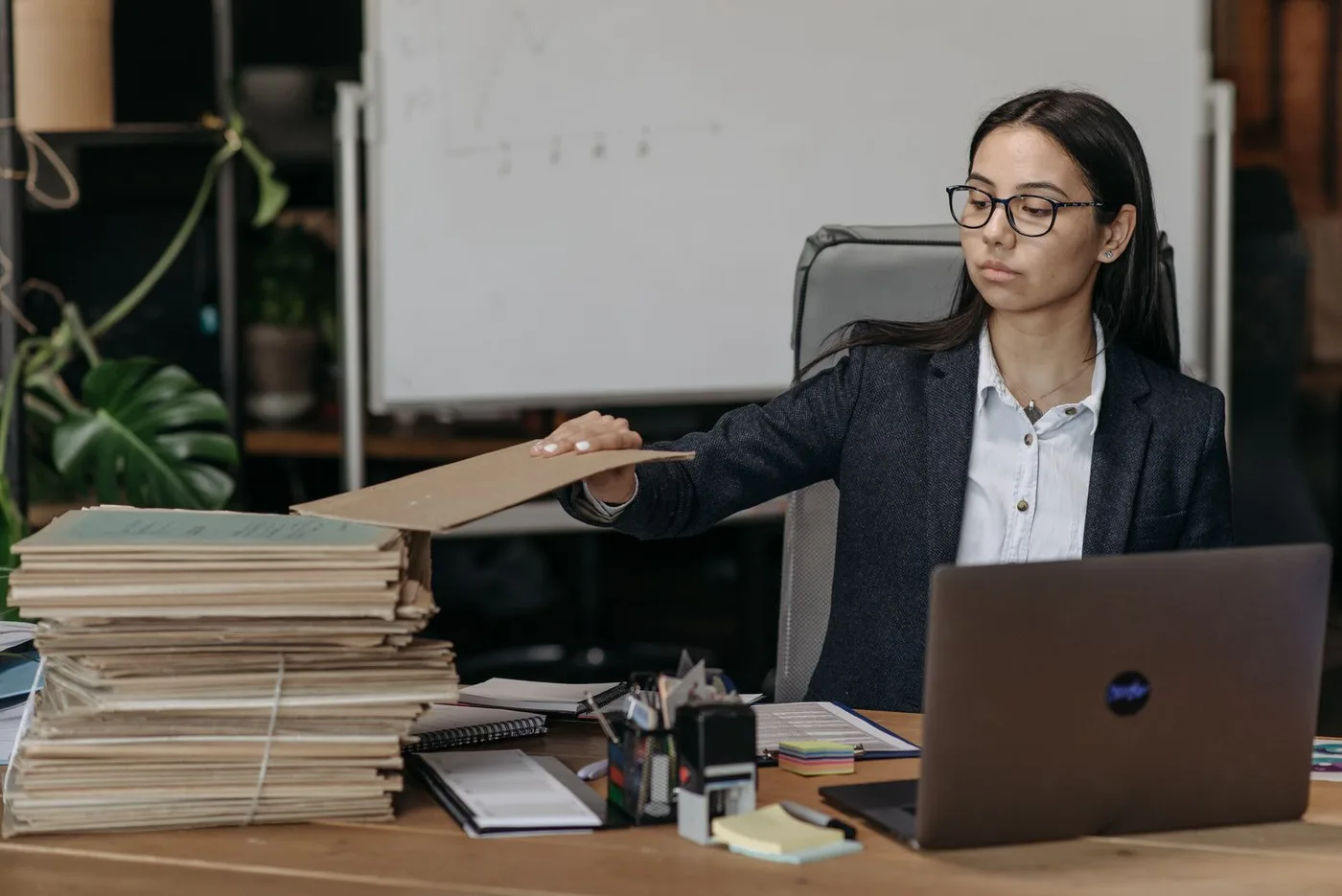 A paralegal working through stacks of files beside her laptop