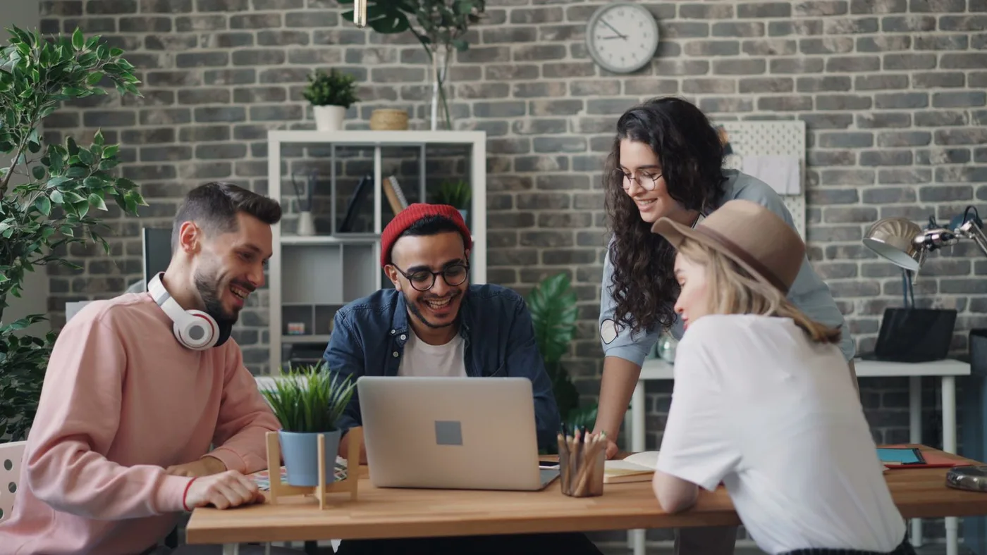 A mixed team gathered around a laptop in the office