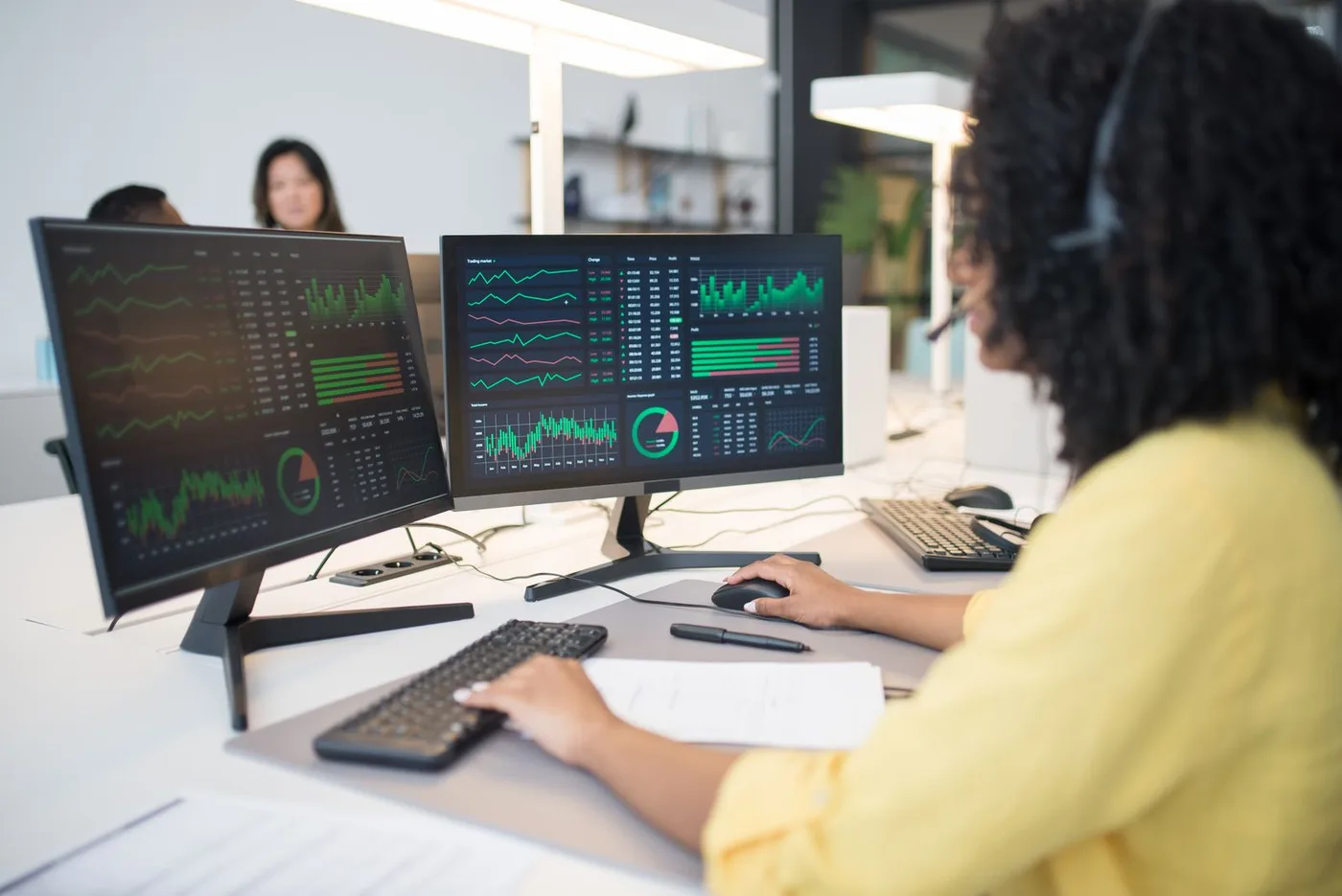 An analyst working across two screens of data