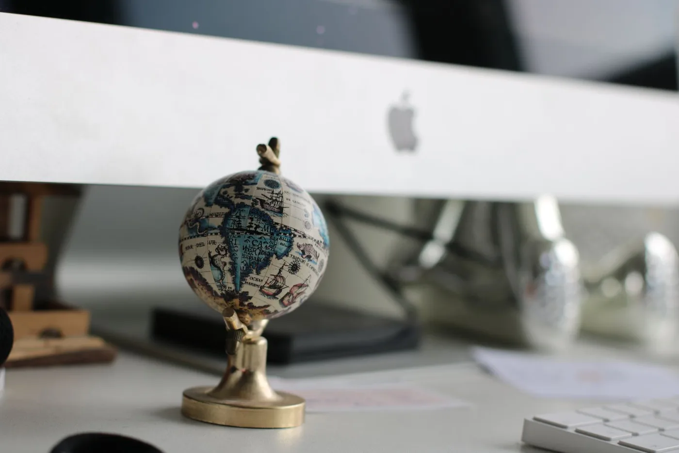 A small globe on a desk in front of a monitor