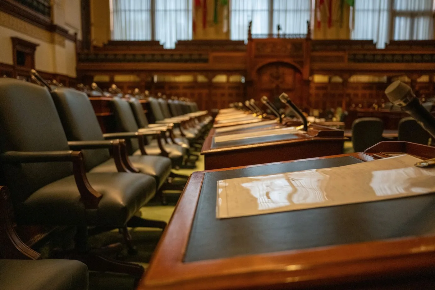 Empty debating chamber with rows of desks and microphones