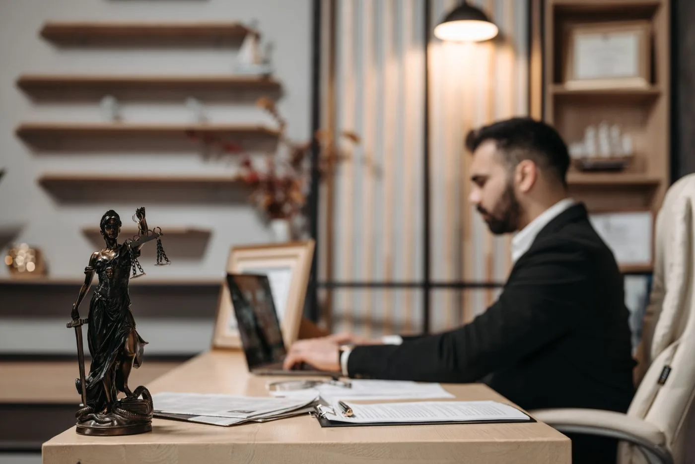 IP professional working on a laptop beside a Lady Justice statue